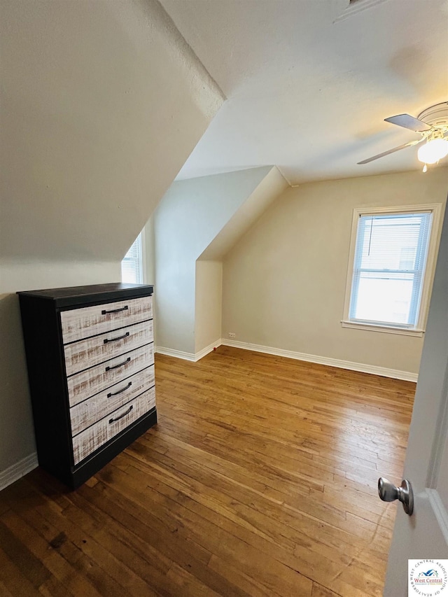 bonus room featuring lofted ceiling, a ceiling fan, baseboards, and dark wood-type flooring