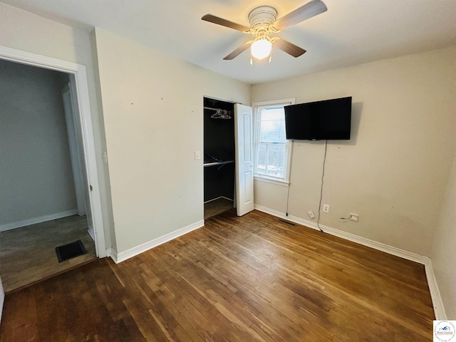 unfurnished bedroom featuring dark wood-style floors, visible vents, baseboards, and a ceiling fan