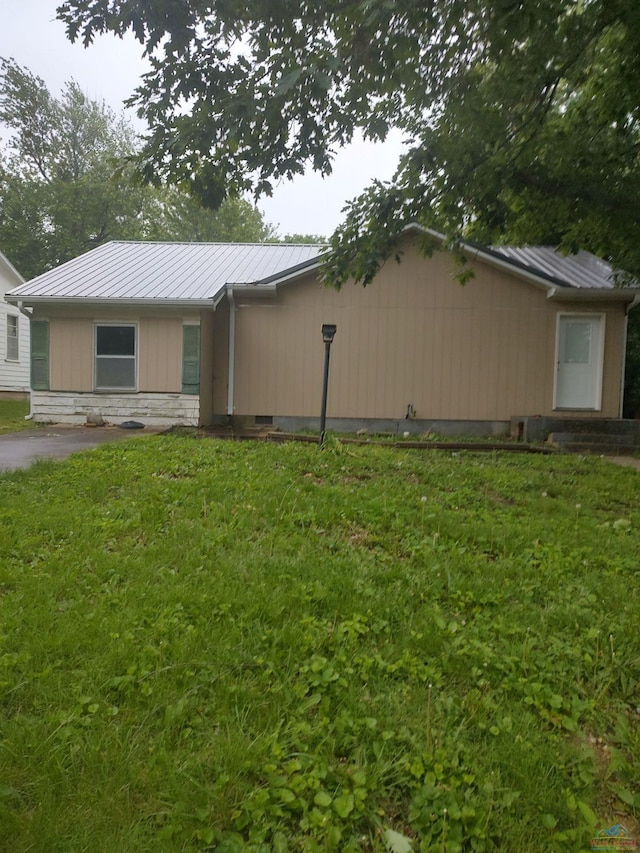 view of home's exterior featuring stone siding, metal roof, and a yard