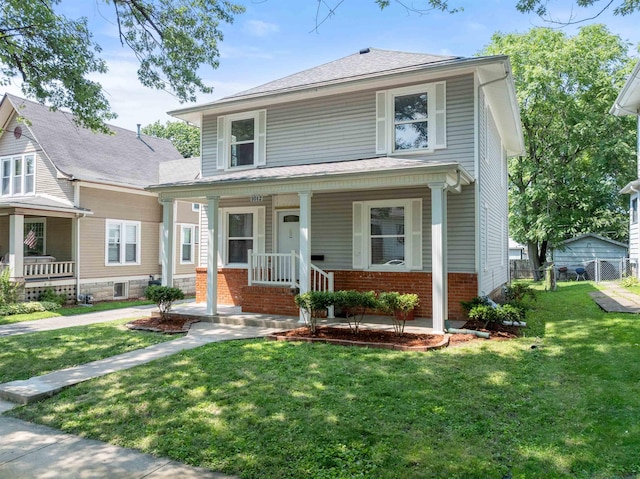 traditional style home with a front yard, covered porch, and brick siding