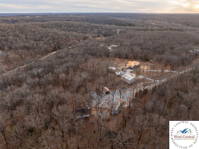 aerial view at dusk featuring a forest view