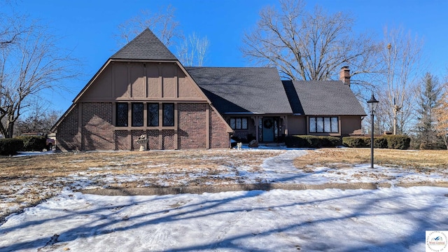 view of front of house with brick siding, a chimney, and roof with shingles