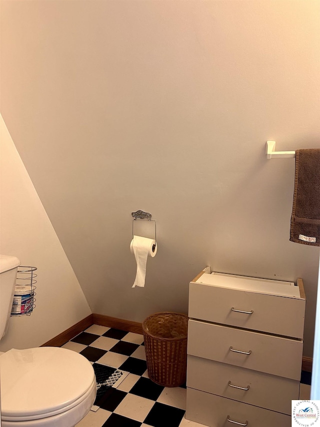 half bathroom with toilet, tile patterned floors, and baseboards