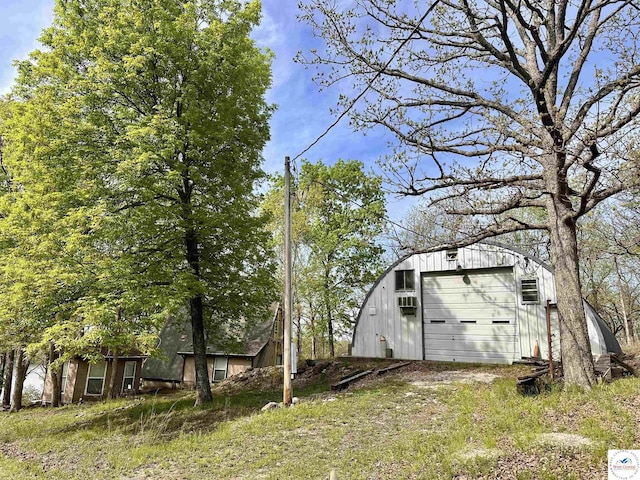 view of yard with driveway, a detached garage, and an outbuilding