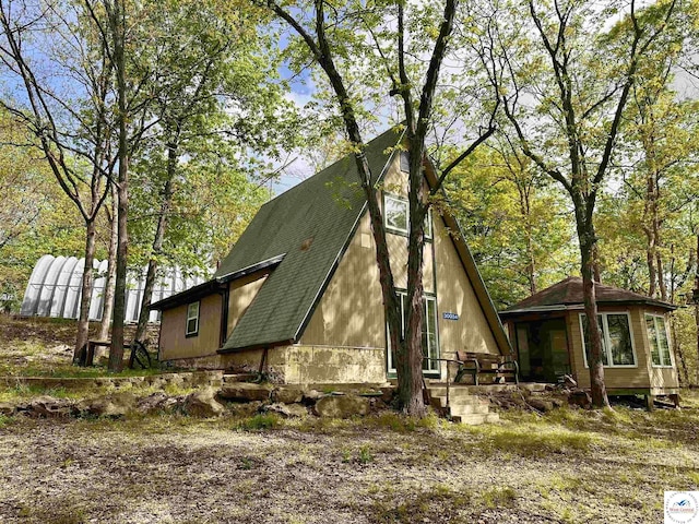 exterior space with a shingled roof and an outbuilding