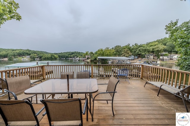 wooden deck with a water view and outdoor dining space