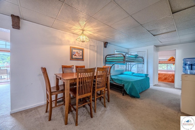 dining area with carpet, baseboards, and a drop ceiling