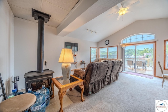 carpeted living area featuring ceiling fan, rail lighting, a wood stove, and lofted ceiling