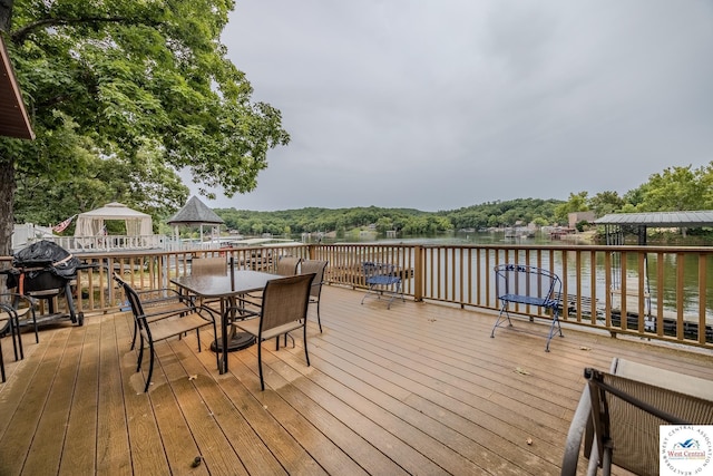 deck with a gazebo, a water view, a grill, and outdoor dining space