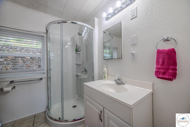 bathroom with tile patterned flooring, a stall shower, vanity, and a textured wall