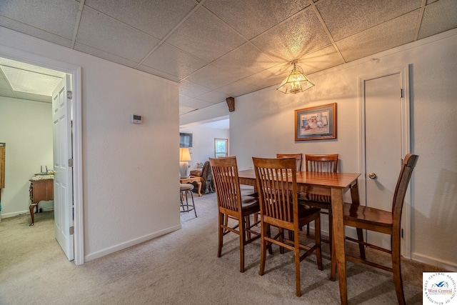 dining space featuring carpet flooring, baseboards, and a drop ceiling