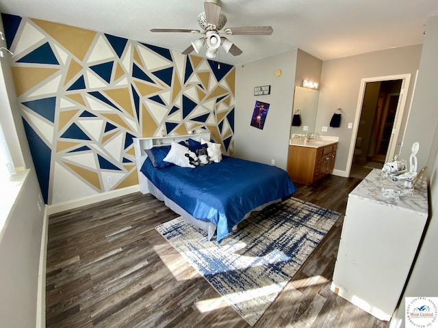 bedroom with ensuite bathroom, a sink, baseboards, and wood finished floors