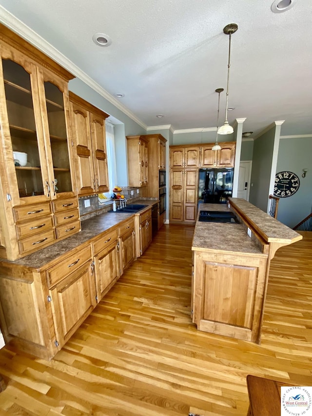 kitchen featuring black appliances, light wood-style flooring, crown molding, and a center island