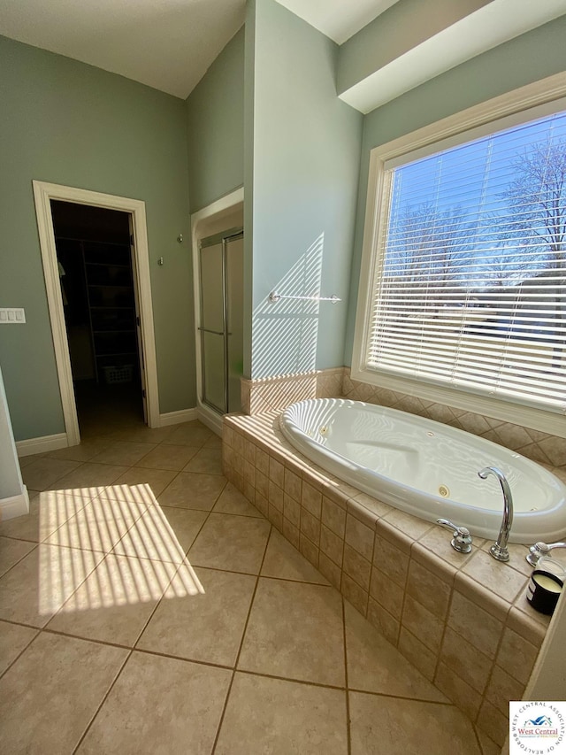 bathroom featuring a walk in closet, a shower stall, tile patterned flooring, baseboards, and a bath