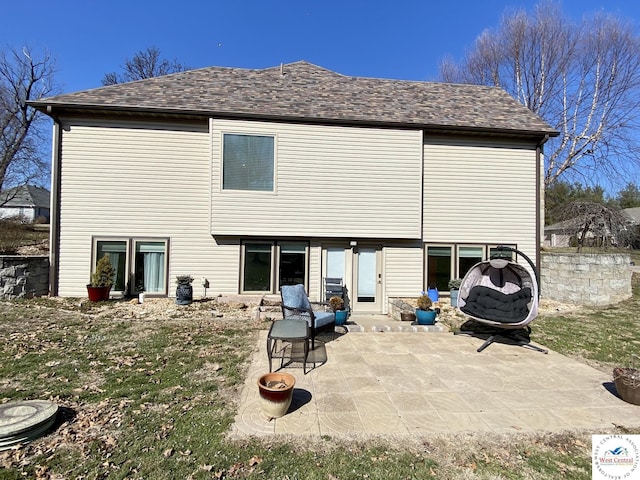 rear view of house featuring a shingled roof and a patio