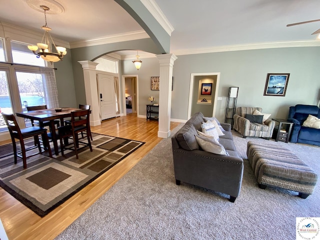 living room featuring ornate columns, arched walkways, wood finished floors, and ornamental molding