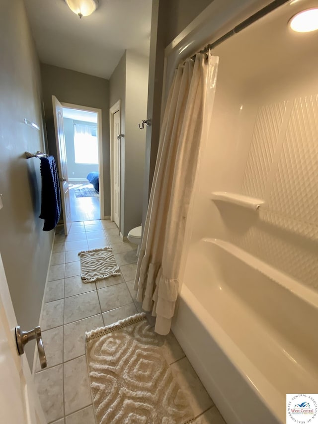 full bath featuring toilet, tile patterned flooring, baseboards, and shower / bath combo with shower curtain