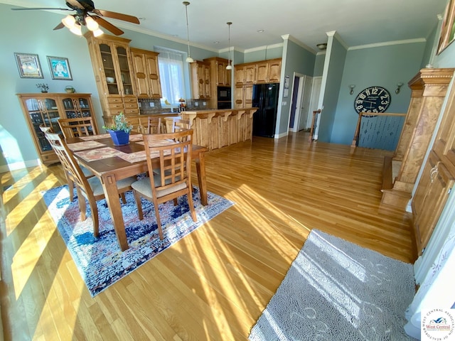 dining area featuring ceiling fan, ornamental molding, baseboards, and light wood-style floors