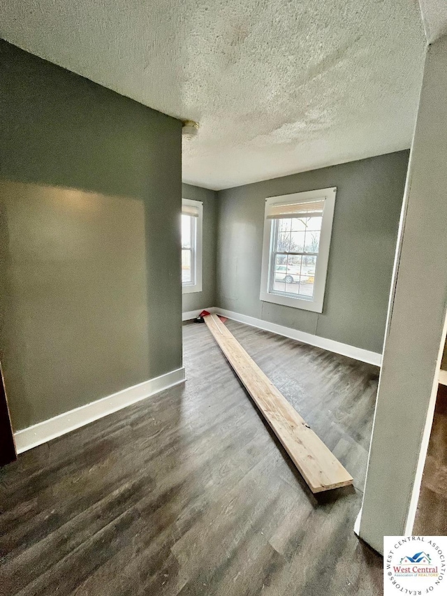 interior space with a textured ceiling, baseboards, and dark wood-style flooring