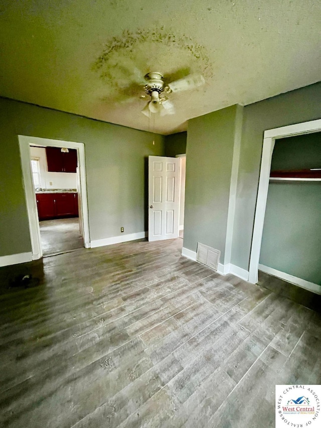 unfurnished bedroom with baseboards, a closet, visible vents, and wood finished floors