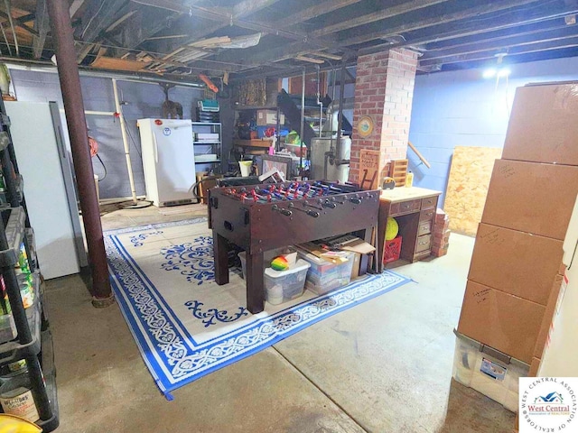 unfinished basement featuring freestanding refrigerator