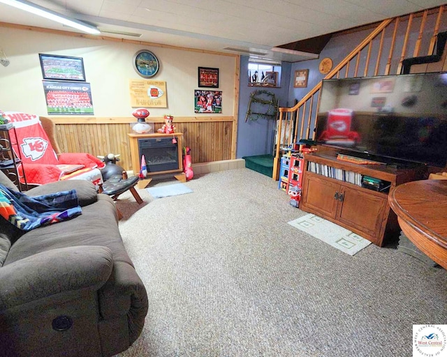 carpeted living area with a wainscoted wall, stairway, and wood walls