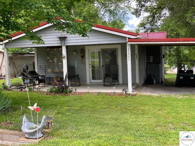 back of property with metal roof, an attached carport, and a lawn