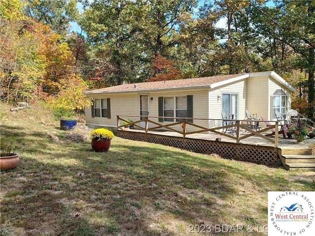 rear view of house with a yard and a wooden deck