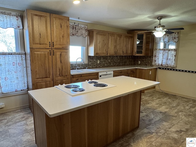 kitchen featuring white appliances, a sink, light countertops, brown cabinets, and glass insert cabinets