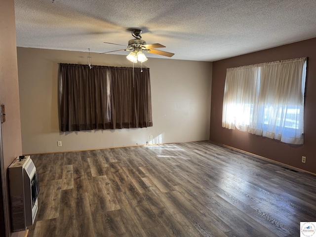 unfurnished room with dark wood-style floors, a textured ceiling, a ceiling fan, and heating unit