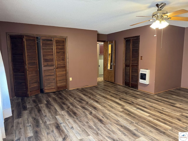 unfurnished bedroom with dark wood-style flooring, heating unit, a closet, a ceiling fan, and a textured ceiling