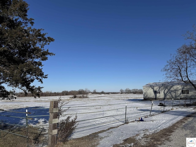 yard layered in snow with fence and a rural view