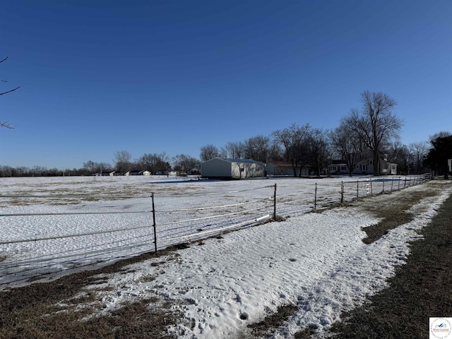 yard layered in snow with fence and a rural view