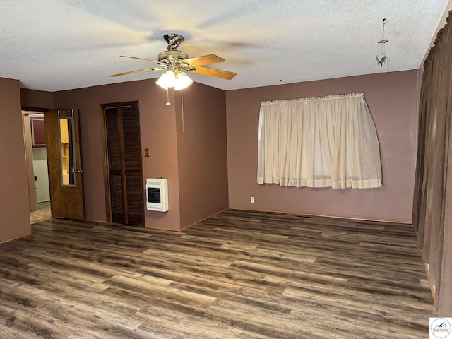 spare room with heating unit, dark wood-style floors, a ceiling fan, and a textured ceiling