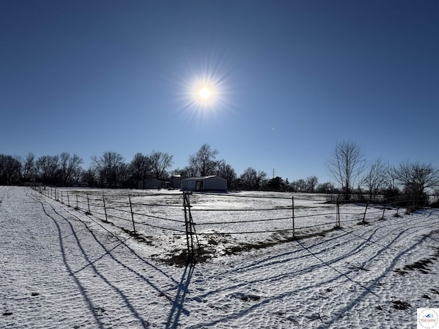 snowy yard featuring fence and a rural view