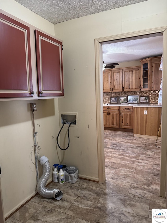 clothes washing area with washer hookup, cabinet space, a ceiling fan, a textured ceiling, and baseboards