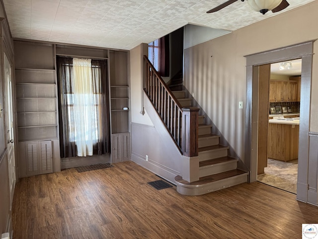 entrance foyer with stairs, a ceiling fan, visible vents, and wood finished floors