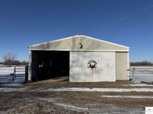 snow covered structure featuring an outbuilding, a pole building, and fence