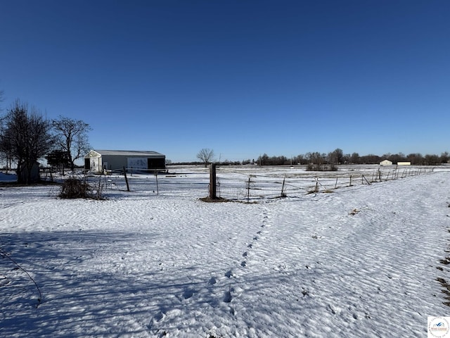 yard layered in snow featuring a rural view and fence