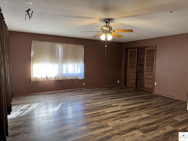 unfurnished bedroom with a textured ceiling, ceiling fan, dark wood-type flooring, and a closet