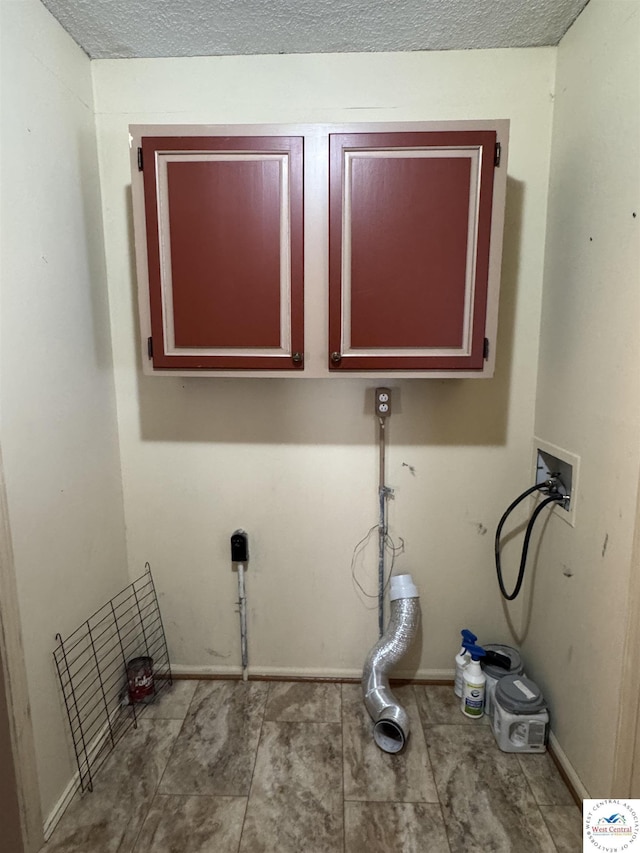 clothes washing area with cabinet space, baseboards, and a textured ceiling