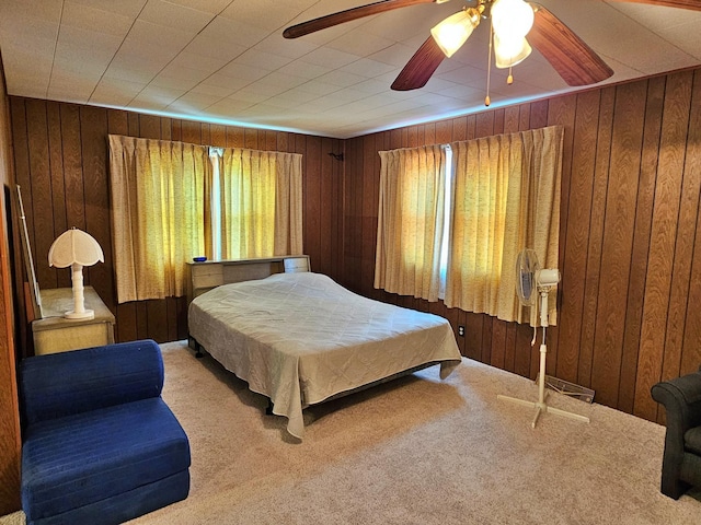 carpeted bedroom with wood walls and ceiling fan