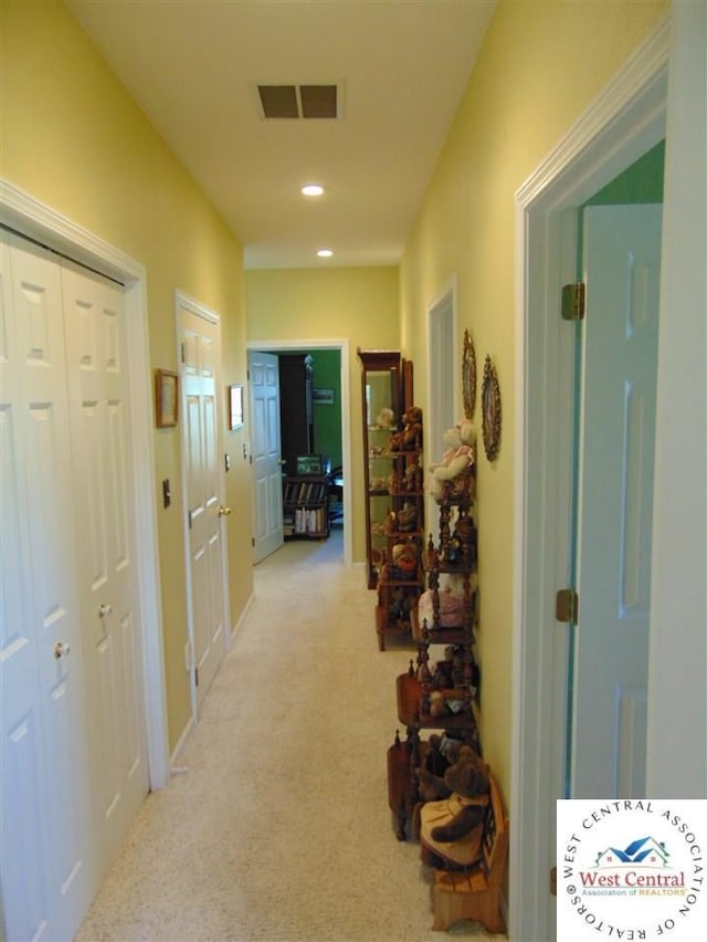 hall featuring recessed lighting, visible vents, and light colored carpet