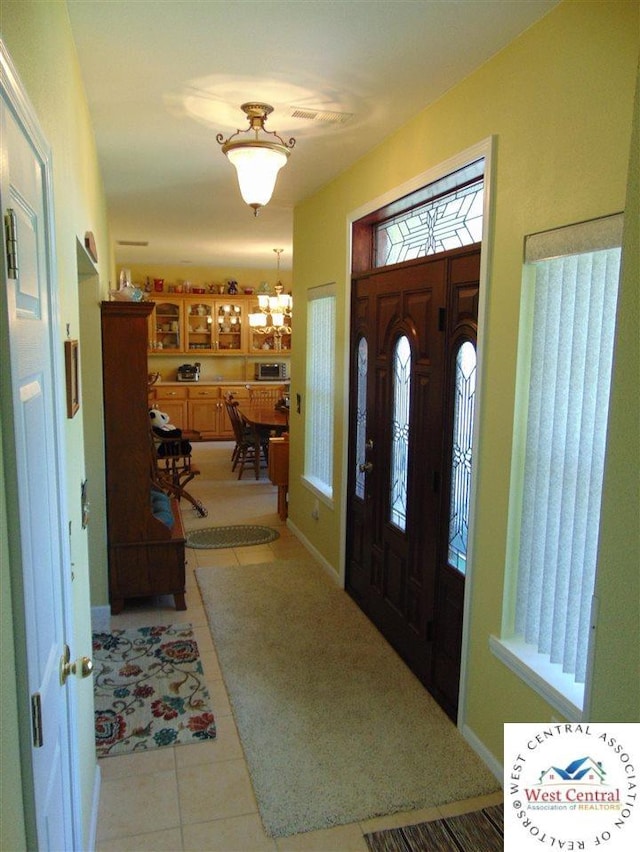 foyer entrance featuring light tile patterned floors and a notable chandelier