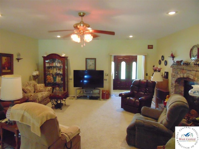 carpeted living area featuring a stone fireplace, recessed lighting, and a ceiling fan