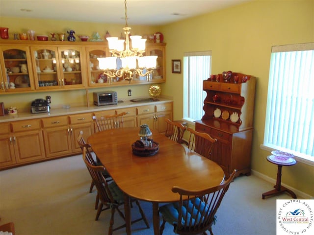 dining area featuring a chandelier, a toaster, light carpet, and baseboards