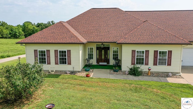 view of front of property featuring an attached garage, roof with shingles, and a front yard