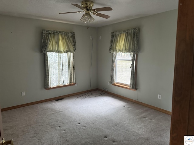 unfurnished room with baseboards, ceiling fan, visible vents, and light colored carpet