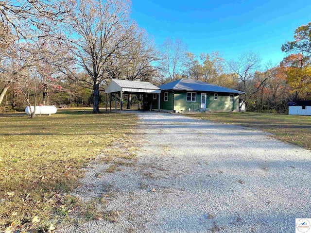 view of front of property with gravel driveway, a front yard, and an attached carport