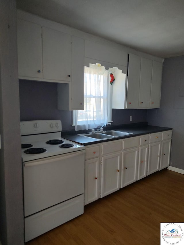 kitchen featuring white range with electric cooktop, dark countertops, white cabinets, a sink, and wood finished floors